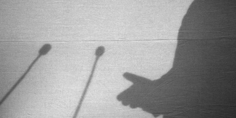 Der Schatten eines Redners während einer Pressekonferenz. Manche Menschen haben eine starke Meinung - oft auch gerne zu wissenschaftlichen Erkenntnissen.
