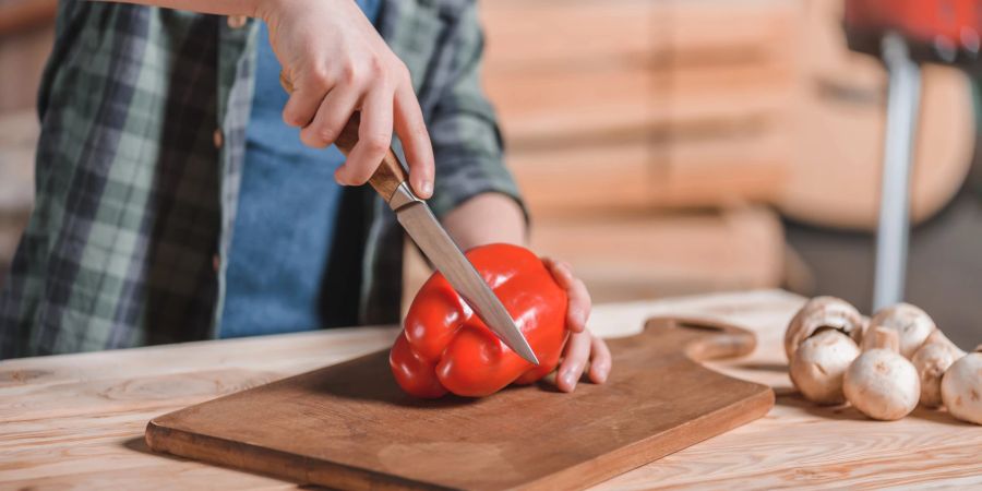 Junge mit Messer schneidet Paprika