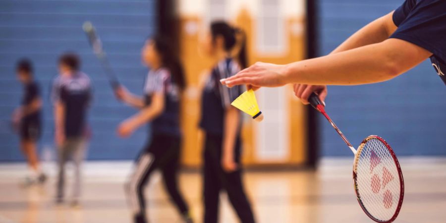 Jugendliche spielen Badminton.