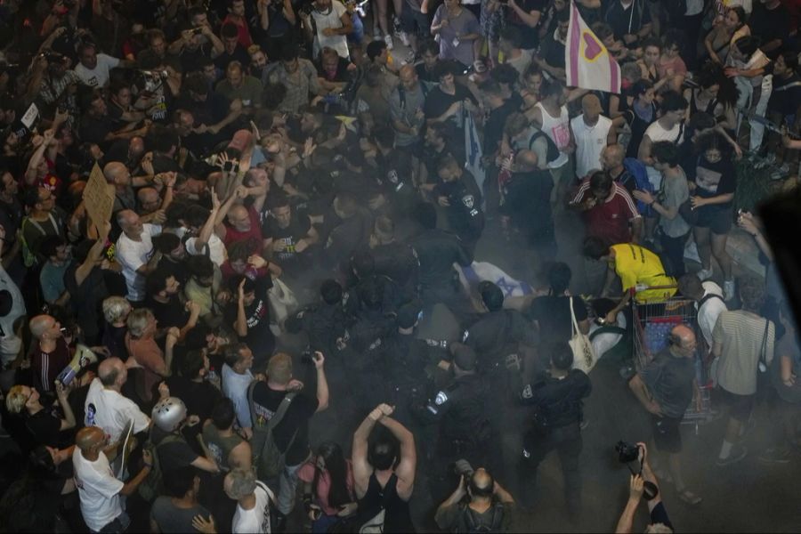 Polizisten drängen Demonstranten beiseite, die eine Strasse blockieren.