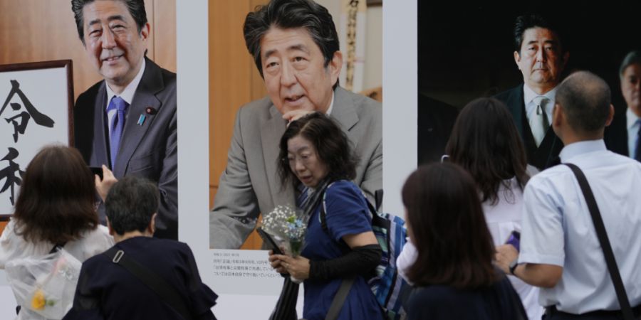 ARCHIV - Menschen betrachten Fotos des ehemaligen japanischen Premierministers Shinzo Abe, bevor sie im Zojoji-Tempel in Tokio beten. Foto: Shuji Kajiyama/AP/dpa