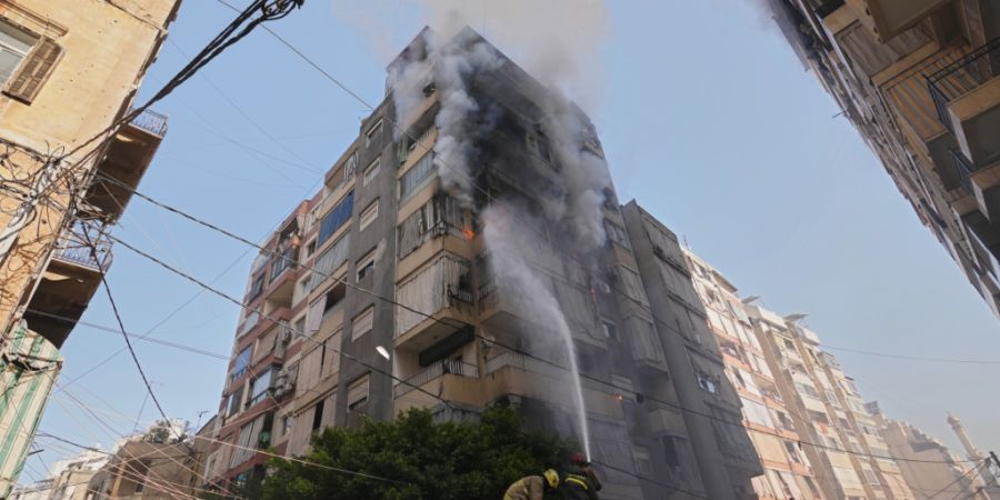 Feuerwehrleute sprühen Wasser auf ein brennendes Wohnhaus nach einem israelischen Luftangriff im Zentrum der libanesischen Hauptstadt. Foto: Hassan Ammar/AP/dpa