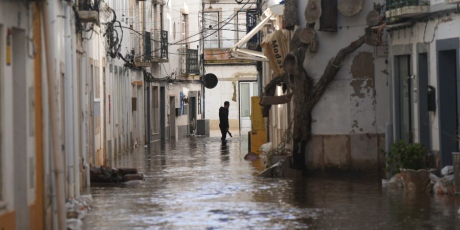 Ein Anwohner geht eine überflutete Straße entlang, nachdem der Fluss Sado nach heftigen Regenfällen in Alcácer do Sal, Südportugal, über die Ufer getreten ist. Foto: Ana Brigida/A...