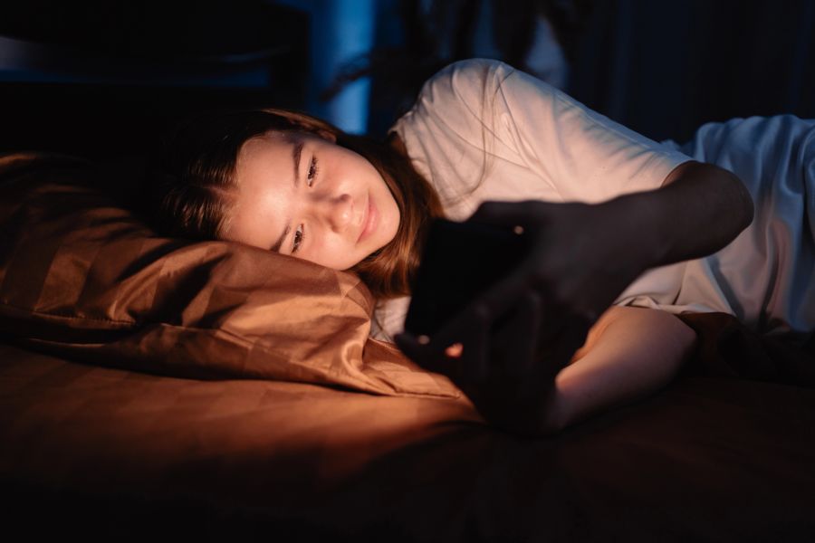 teenager mit smartphone im bett