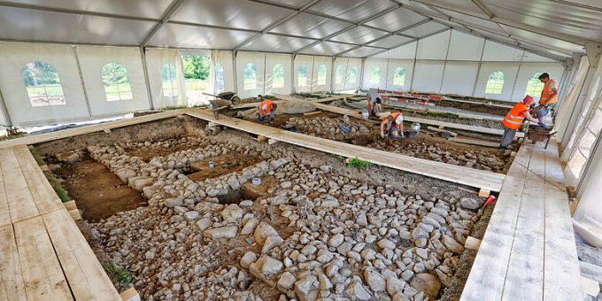 Blick auf einen Teil der freigelegten Mauern mit bereits erkennbarer Raumaufteilung. Im Raum im Bildvordergrund sind noch Reste der Bodenkonstruktion erhalten. Raumaufteilung