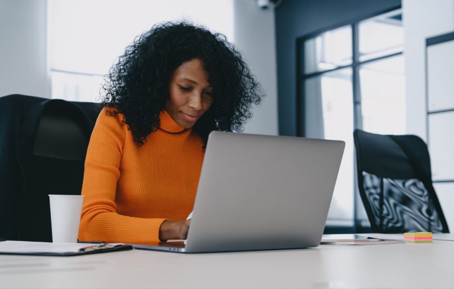 frau im orangenen pulli vor laptop