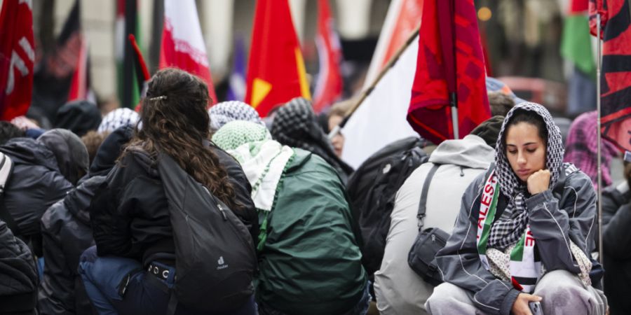 Schweigeminute in der geschäftigen Bahnhofstrasse. Rund tausend Demonstrierende kauern bei der Zürcher Palästina-Kundgebung auf der Strasse.