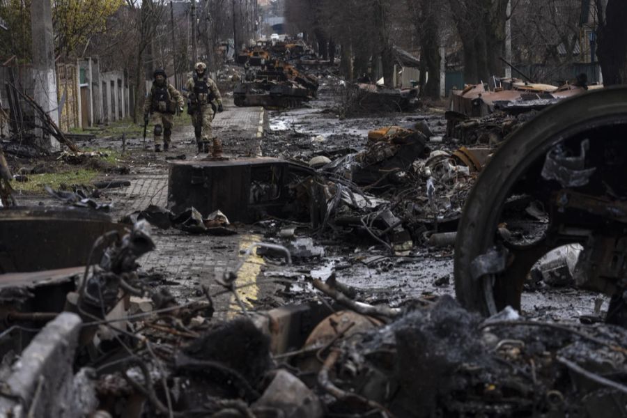 Soldaten gehen zwischen zerstörten russischen Panzern in Butscha, einem Aussenbezirk von Kiew, spazieren.