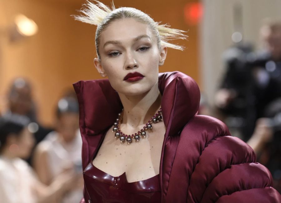 Gigi Hadid trägt eine Perlenkette zu ihrem burgunderroten Prachtkleid.