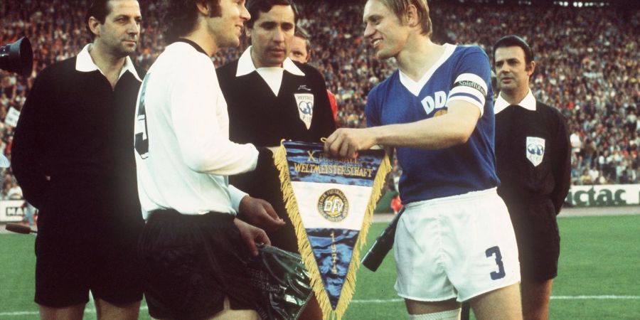 DDR-Auswahl-Kapitän Bernd Bransch (r) 1974 beim Wimpeltausch mit Franz Beckenbauer.