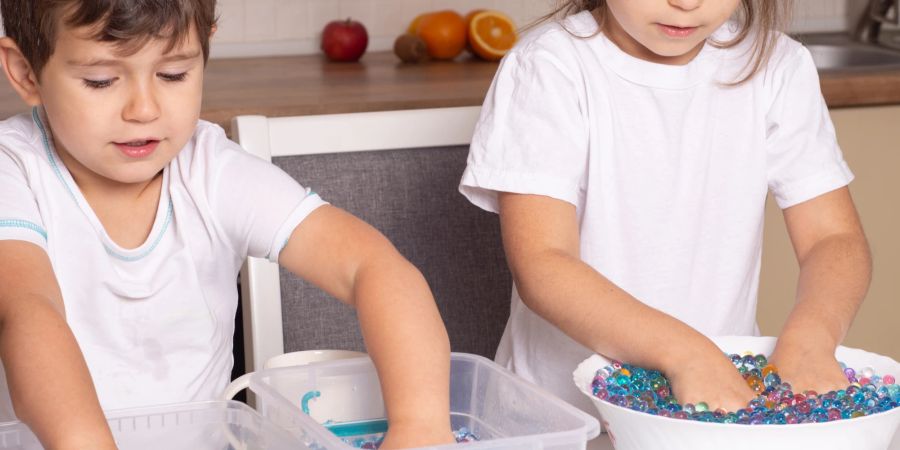 Kinder spielen mit Wasserperlen