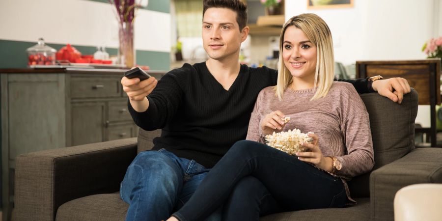 paar sitzt auf Sofa und schaut gemeinsam fern, popcorn