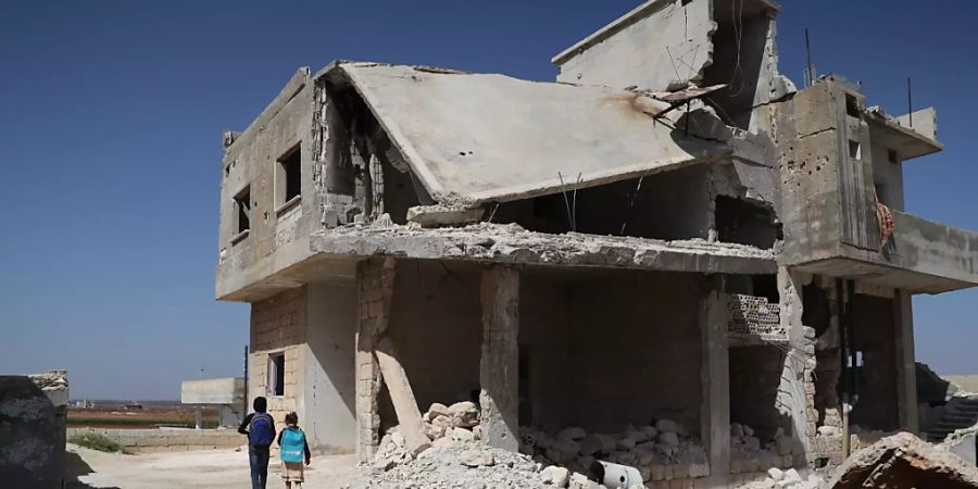 Kinder laufen an einem zerstörten Haus in Idlib vorbei, nachdem sie ihre Schule zu Beginn des Schuljahres verlassen haben. Foto: Anas Alkharboutli/dpa