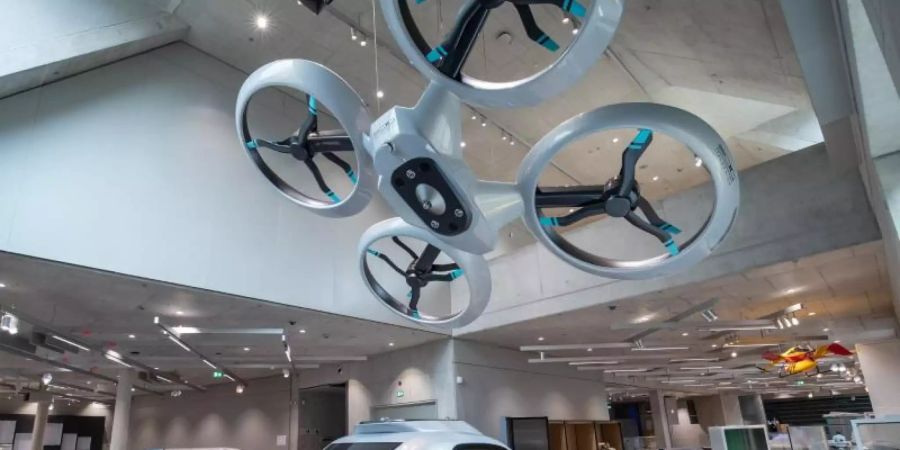 Die Passagierdrohne "Pop.Up Next" (v) steht in den Ausstellungsräumen vom Zukunftsmuseum, der Zweigstelle des Deutschen Museums München, neben dem Prototyp für das Hyperloop-Projekt (M) und das Solarauto blue.cruiser (l). Foto: Daniel Karmann/dpa
