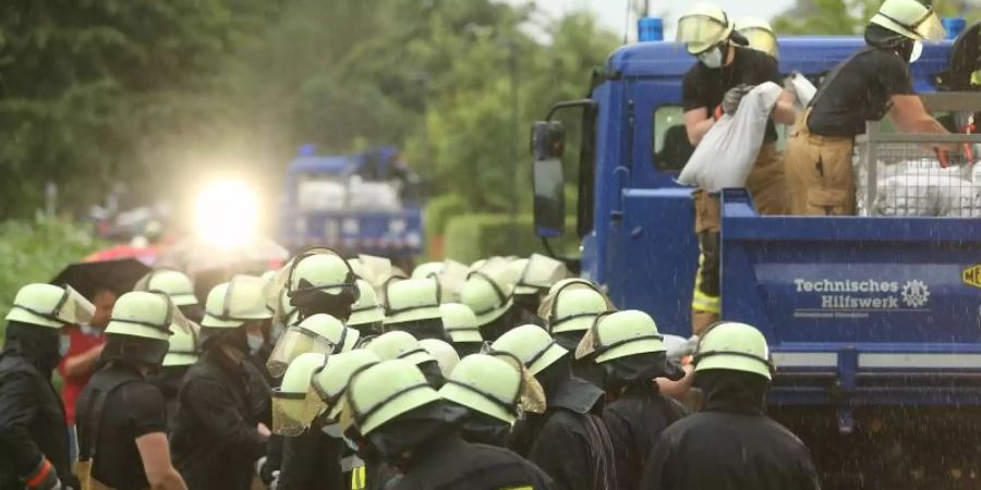 Die Feuerwehr versucht, die Wassermassen mit Sandsäcke zu stoppen. Foto: David Young/dpa
