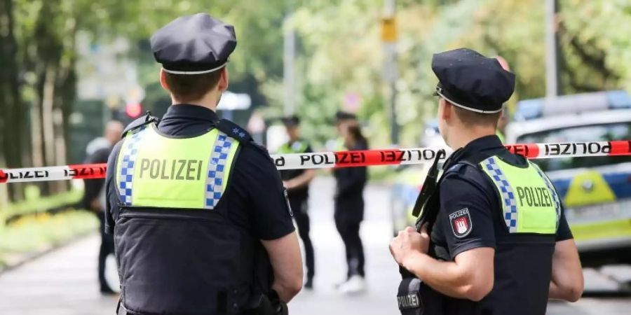 Einsatzkräfte stehen während des Einsatzes am Freitag an einer Absperrung auf dem Gorch-Fock-Wall in Hamburg. Foto: Bodo Marks/dpa