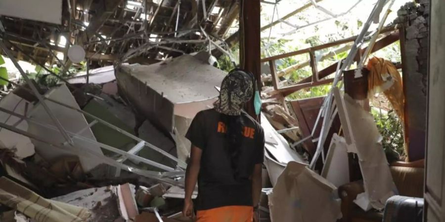 Ein Rettungshelfer inspiziert ein zerstörtes Haus im Dorf Nganjuk. Foto: Trisnadi/AP/dpa