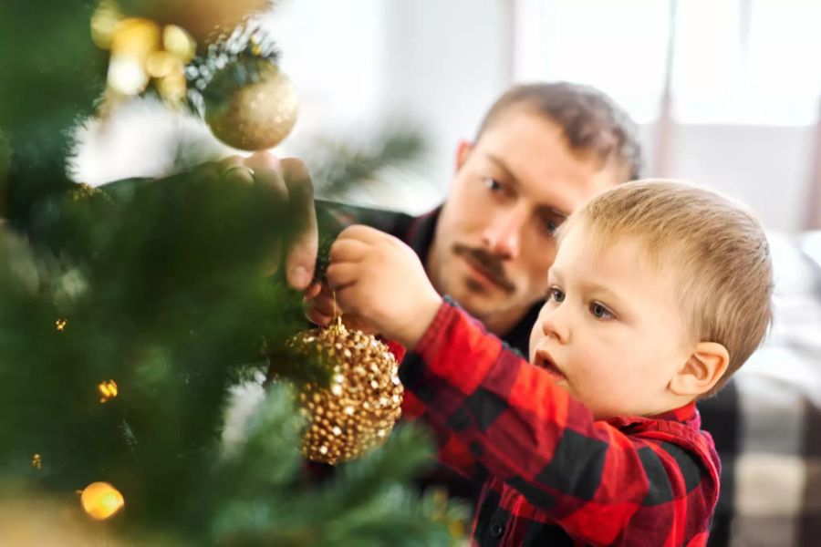 Junge schmückt Weihnachtsbaum