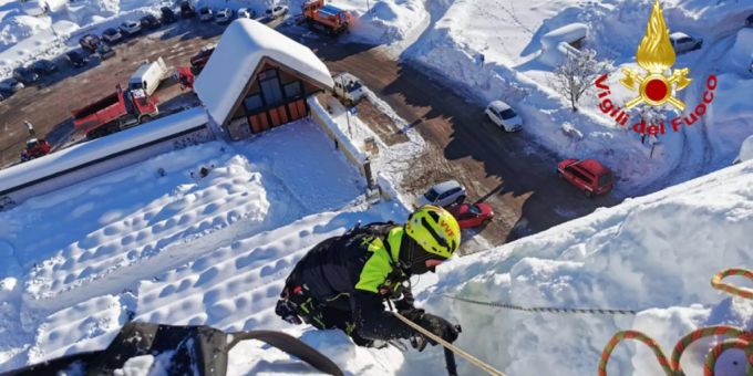 Ein Feuerwehrmann hilft bei der Schneeräumung und -sicherung auf dem Dach der Kirche Santa Margherita in dem Dorf in der nordöstlichen Region Friaul-Julisch Venetien. italien schnee