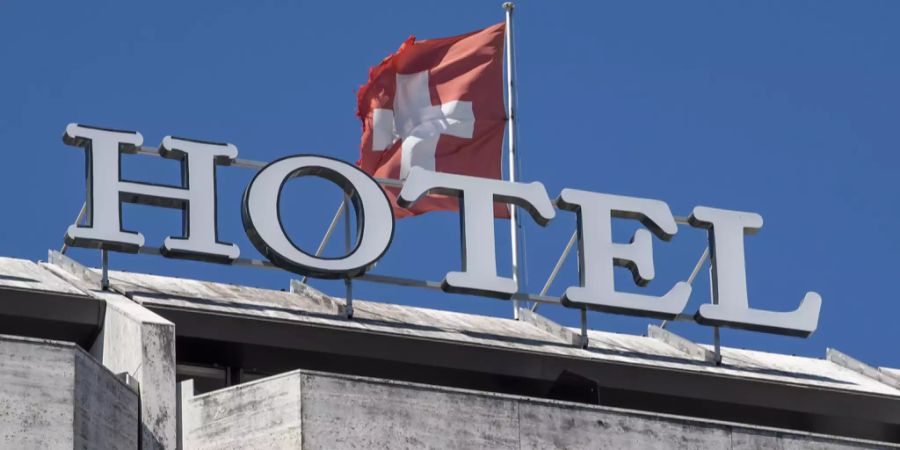 Die Schweizer Fahne weht im Wind auf dem Dach eines Hotels.