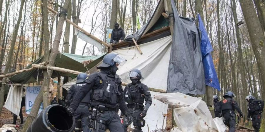 Polizisten räumen in einem Protest-Camp im Dannenröder Forst Gegenstände aus dem Weg. Foto: Boris Roessler/dpa