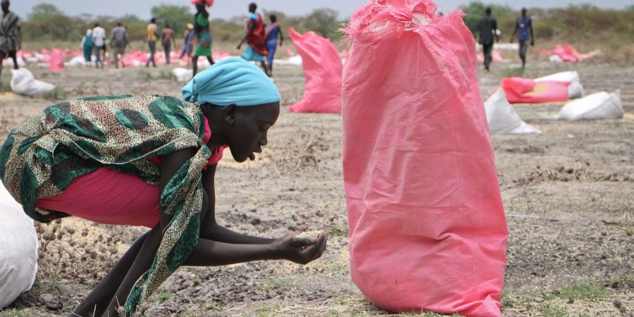 Eine Frau sammelt Hirse vom Boden auf, die in Säcken vom Welternährungsprogramm (WFP) der Vereinten Nationen über Kandak im Südsudan abgeworfen wurden.