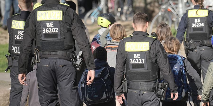 Polizisten geleiten Kinder weg vom Tatort an der Schule in Berlin-Neukölln.