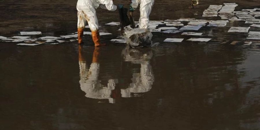 Arbeiter sammeln am Strand von Mae Ramphueng in Thailand mit Öl verschmutzes Material ein. Foto: Nava Sangthong/AP/dpa