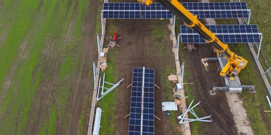 Mit einem Kran wird eine Agrar-Photovoltaik-Anlage in Niedersachsen montiert. Foto: Philipp Schulze/dpa