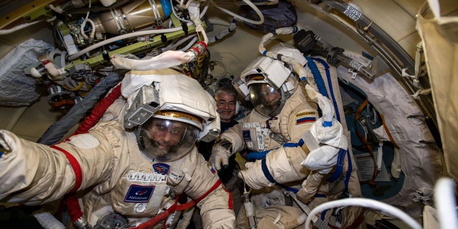 Die russischen Kosmonauten Anton Schkaplerow (l) und Pjotr Dubrow (r) bereiten sich mit Unterstützung von NASA-Astronaut Mark Vande Hei (hinten)  auf einen Weltraumspaziergang vor.