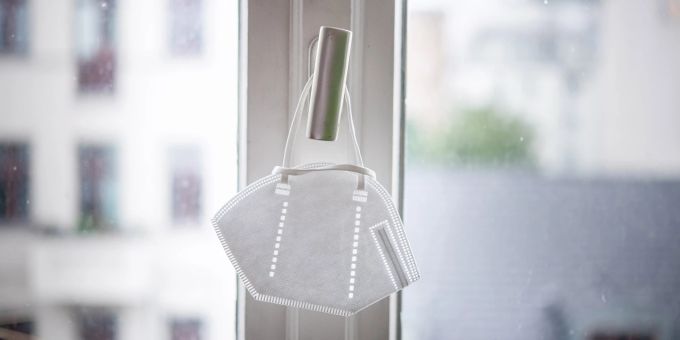 Offiziell genesen – und doch noch nicht wieder fit. Ein Teil der Long-Covid-Betroffenen erlebt große Erschöpfung. Mundschutz weiss Fensterrahmen Griff Metall