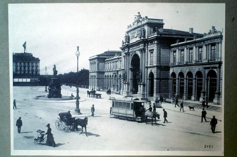 1862 wurde in Genf das erste Tram eröffnet, wobei noch Pferde die schweren Wagen über die Schienen zogen. Grosse Städte wie Winterthur, Luzern, Basel (wobei hier Rösslitrams ohne Schienen, sogenannte «Pferdeomnibusse», im Einsatz waren), Biel und Bern zogen bald nach. Auf dem Bild sehen wir den Bahnhof Zürich mit dem 1889 eingeweihten Denkmal des Bahnpioniers und Vorsitzenden der Gotthardbahn-Gesellschaft Alfred Escher.