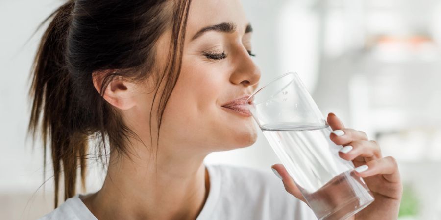 dunkelhaarige frau trinkt aus wasserglas