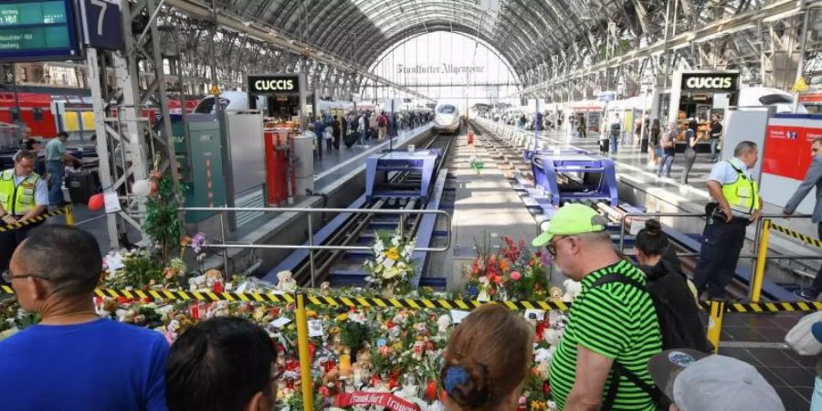 Passanten stehen 2019 im Frankfurter Hauptbahnhof vor Blumen, Kuscheltieren und Beileidsbekundungen. Foto: Arne Dedert/dpa
