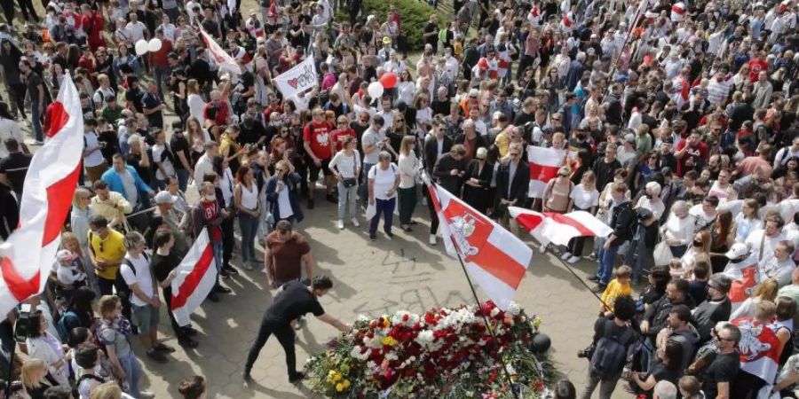 Menschen sammeln sich am Ort, an dem ein Demonstrant getötet wurde, und legen Blumen nieder. Foto: Dmitri Lovetsky/AP/dpa