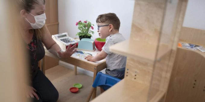 Eine Physiotherapeutin mit Hygienemaske arbeitet mit einen Jungen in der Kita 6e der Stiftung GFZ, aufgenommen am 9. Juli 2020 in Zürich. Kita Maskenpflicht