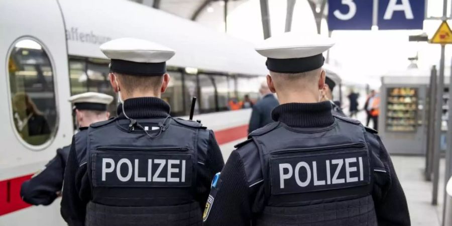 Bundespolizisten stehen vor der Abfahrt eines ICE an einem Gleis im Kieler Hauptbahnhof. In den Zügen der Deutschen Bahn wird die Mund-Nase-Bedeckungspflicht kontrolliert. Foto: Axel Heimken/dpa