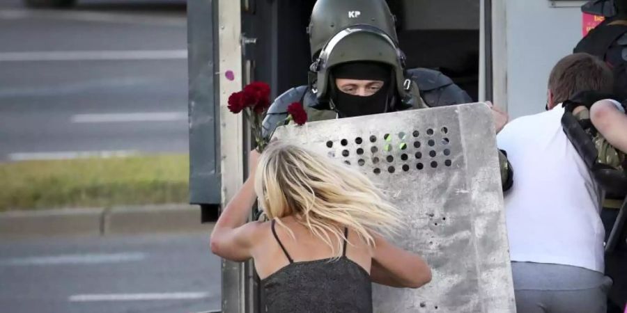 Eine Frau im Clinch mit einem Polizisten, nachdem viele Demonstranten festgenommen worden sind. Foto: -/AP/dpa