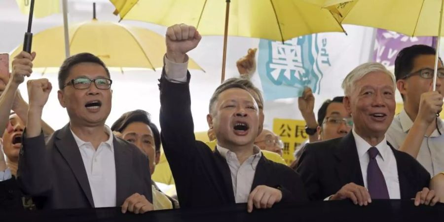 Die Anführer der «Regenschirm-Bewegung», Chan Kin Man (l-r), Benny Tai und Chu Yiu Ming rufen Parolen, bevor sie ins Gericht gehen. Foto: Kin Cheung/AP