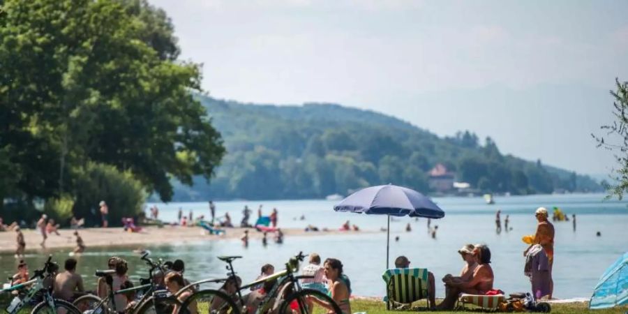 Badegäste liegen am Starnberger See an einem Strand. Der Landkreis ist der reichste in Deutschland. Foto: Lino Mirgeler