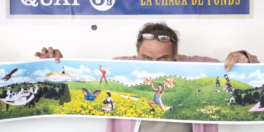 Jacques Froidevaux vom Künstlerkollektiv Plonk & Replonk posiert mit dem Entwurf eines Monumentalgemäldes, das in La Chaux-de-Fonds installiert werden soll. Anlass ist die 2009 erfolgte Aufnahme der Stadt in die Liste der UNESCO-Welterbestätten 2009.