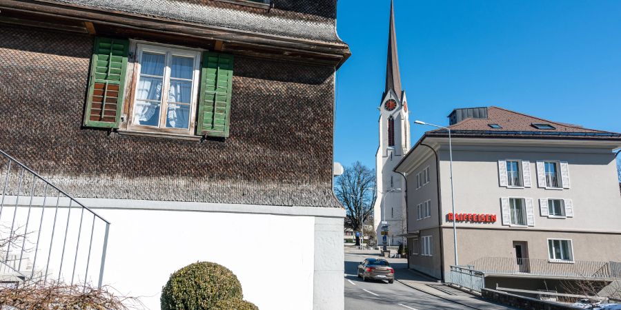 Ein Schindelhaus, die katholische Kirche und die Raiffeisenbank an der Hauptstrasse in Escholzmatt.