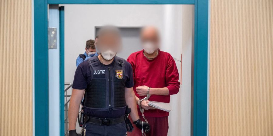 Ein Justizbediensteter begleitet den 52-jährigen Angeklagten (r) zum Prozess um die tödliche Amokfahrt in Trier in den Gerichtssaal des Landgerichts. Er war am 1. Dezember 2020 in einem Auto durch die Innenstadt von Trier gerast und hat dabei fünf Menschen getötet.