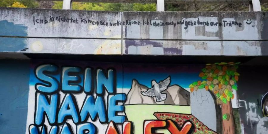 Auf einer Mauer entlang ein Graffiti "Sein Name war Alex" für den getöteten Tankstellen-Mitarbeiter gemalt. Foto: Oliver Dietze/dpa
