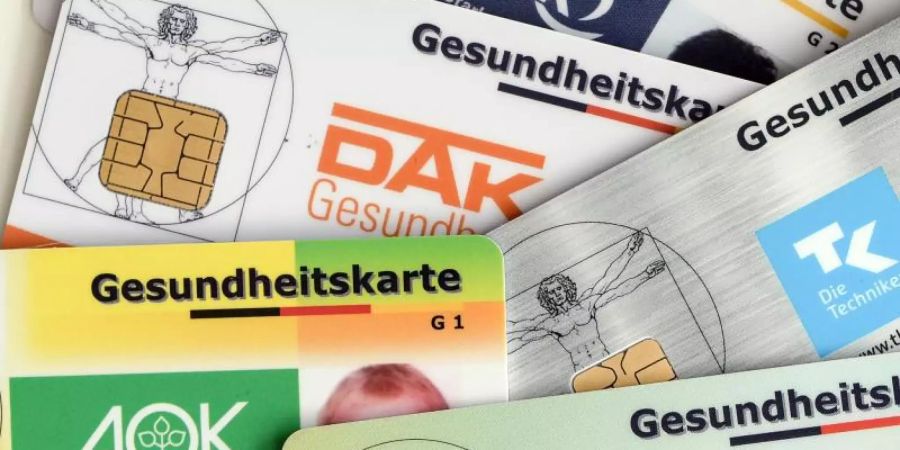 Gesundheitskarten verschiedener Krankenkassen liegen auf einem Tisch. Foto: Jens Kalaene/ZB/dpa