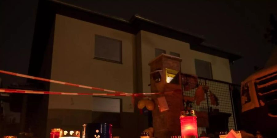 Kerzen brennen auf dem Gehweg vor dem Einfamilienhaus Königs Wusterhausen, wo Polizisten eine Familie tot aufgefunden hatten. Foto: Christophe Gateau/dpa