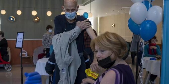 Ein Mann zieht sein Hemd hoch, während seine Frau ihre vierte Dosis des Coronavirus-Impfstoffs in einem privaten Pflegeheim in Petah Tikva erhält. Foto: Ariel Schalit/AP/dpa Ein Mann zieht sein Hemd hoch, während seine Frau ihre vierte Dosis des Coronavirus-Impfstoffs in einem privaten Pflegeheim in Petah Tikva erhält. Foto: Ariel Schalit/AP/dpa