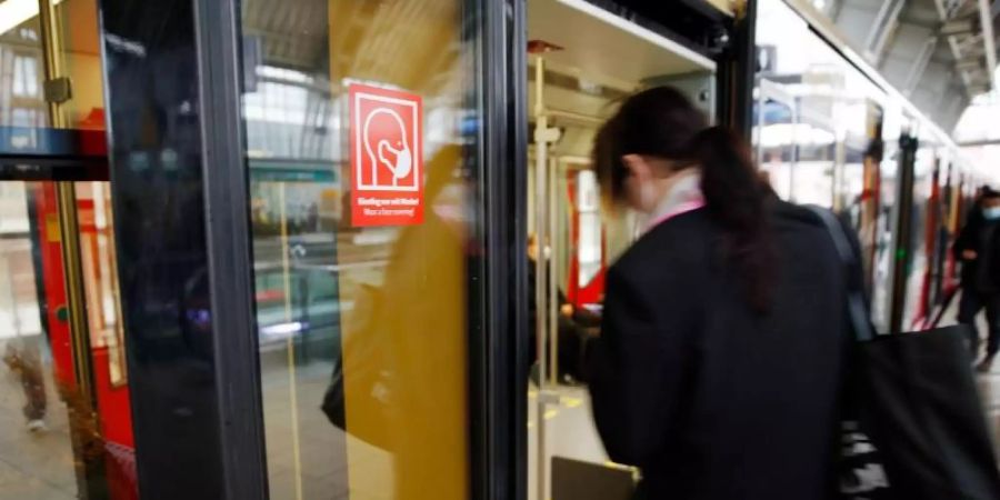 Rote Schilder weisen auf der S-Bahn Tür auf die Pflicht zum Tragen einer Maske hin. Foto: Carsten Koall/dpa