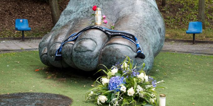 Blumen und Kerzen liegen an der überdimensionalen Bronzeskulptur vom rechten Fuss von Uwe Seeler in Hamburg. Uwe Seeler