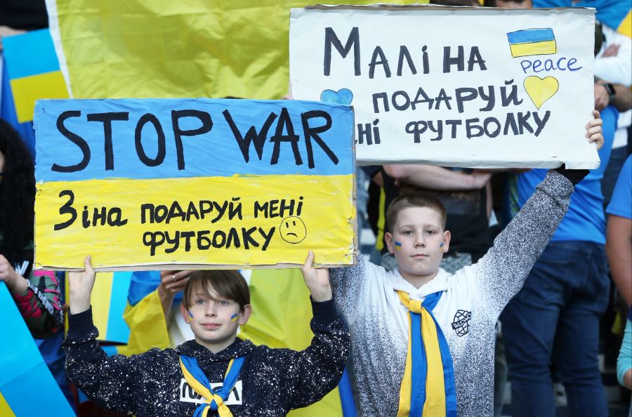 Fans der Ukraine halten vor dem Spiel gegen Schottland Anti-Kriegs-Banner in die Höhe.